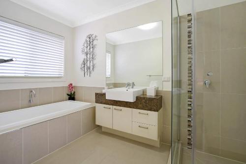 亚勒旺加The Grand Holiday House的一间带水槽、浴缸和镜子的浴室