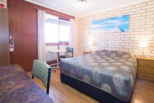 奥古斯塔港奥古斯塔经济汽车旅馆的一间卧室配有一张床、一张桌子和一个窗户。