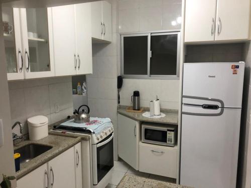 弗洛里亚诺波利斯Apto aconchegante 100m Shopping Beiramar的厨房配有白色橱柜和白色冰箱。