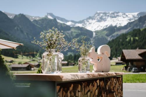 阿德尔博登Wildstrubel Lodge的两瓶玻璃瓶,在桌子上放着鲜花,还有山