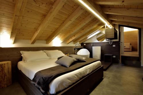 BiennoHotel Oasi Verde的一间带一张大床的卧室,位于一个拥有木制天花板的房间