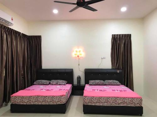 太平Family Homestay的卧室内的两张床,配有粉红色的床单和吊扇