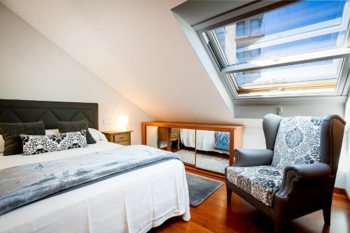 巴约讷Apartamentos Villa Zoila Baiona的卧室配有床、椅子和窗户。