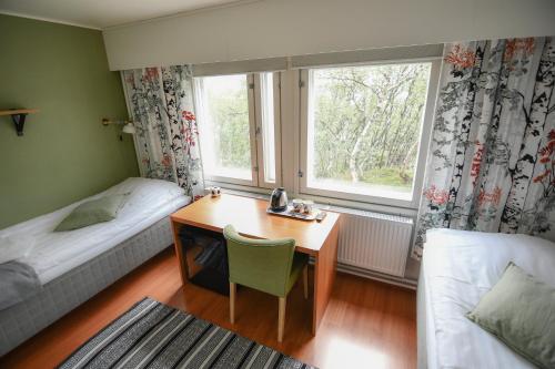 基尔匹斯扎我维Kilpisjärven Retkeilykeskus Rooms的一间卧室配有书桌、床和窗户。