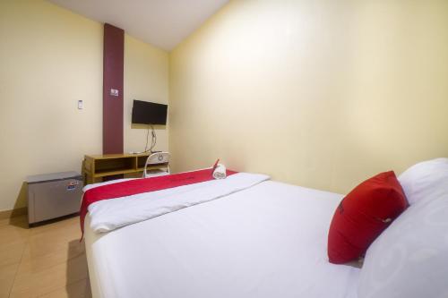 TelagaRedDoorz near TVRI Gorontalo的一间卧室配有两张带红色枕头的床