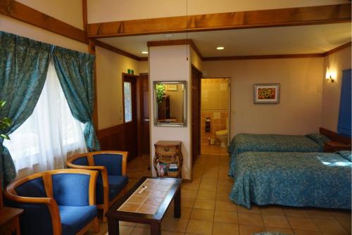 富士河口湖Private Hotel Rei的酒店客房带两张床和一张桌子以及椅子。