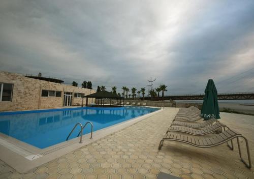 阿纳克利亚棕榈滩酒店的一个带两把椅子和遮阳伞的游泳池