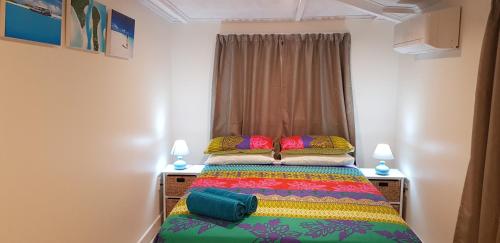 拉罗汤加Te Etu Villa 2的一间卧室配有一张带彩色毯子的床