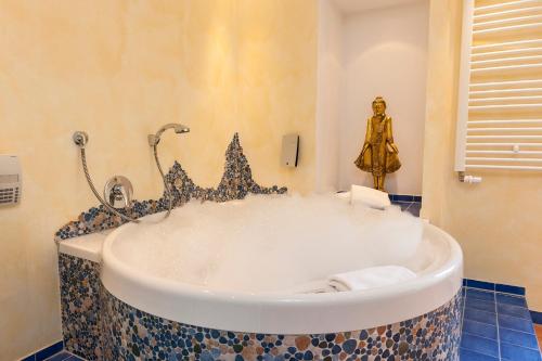 巴特基辛根BRISTOL Hotel Bad Kissingen的带浴缸的浴室和雕像
