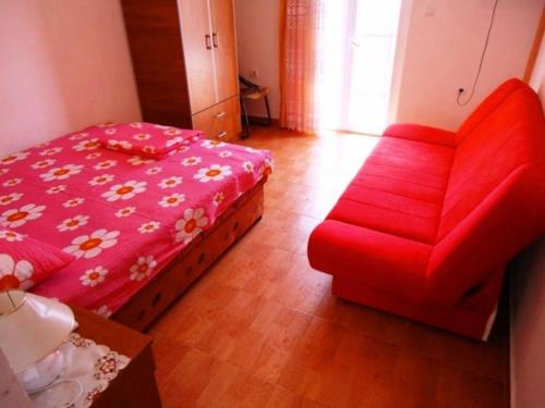 伊加洛Apartments Sun Igalo Montenegro的红色的沙发和客房内的一张床