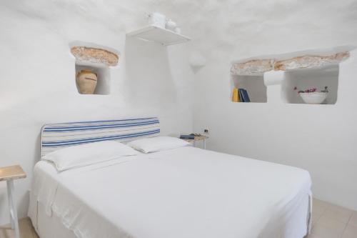 拉卡莱VILLATRULLO MELOGRANO的一间白色卧室,配有床和2个架子