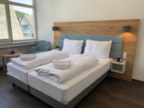 蒙绍besttime Hotel Monschau的一张配有白色床单和枕头的大床