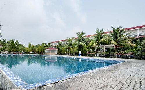Bāgnān索娜邦拉科拉加特酒店的一座棕榈树大型游泳池和一座建筑