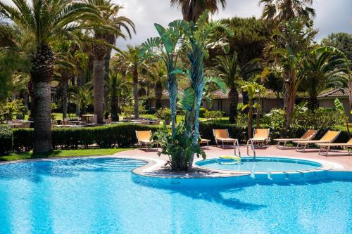 梵蒂冈角Baia Del Sole Resort的度假村内带椅子和棕榈树的游泳池