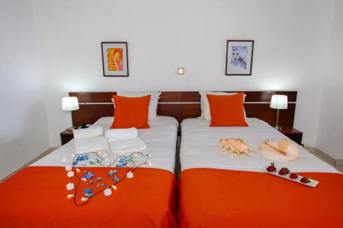 蓬塔德尔加达Aparthotel Barracuda的一间卧室配有两张带橙色枕头的床