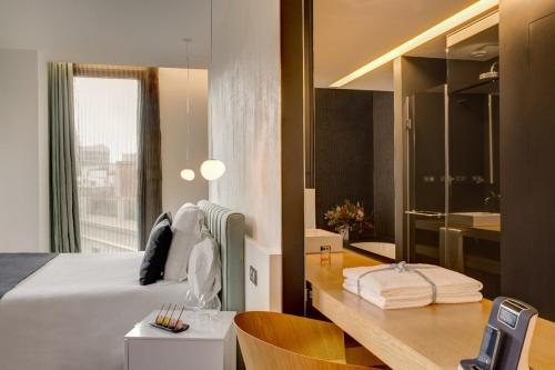 巴塞罗那巴塞罗那奥拉酒店的一间带一张床和一张书桌的卧室以及一间浴室。