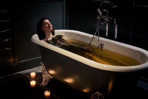 纳斯鱼鹰酒店 的女人站在带蜡烛的浴缸里