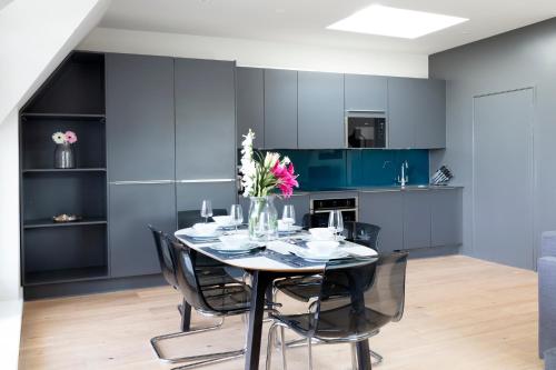 温莎Hampden Apartments - The Richard的一间设有蓝色橱柜和鲜花桌的用餐室