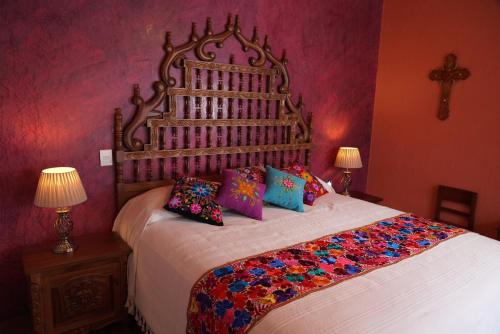 瓜达拉哈拉CASA ALFAREROS的一间卧室配有一张带色彩缤纷枕头的大床