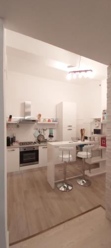 卡利亚里Suite 332的厨房配有白色橱柜、桌子和凳子