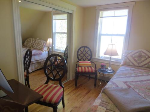 MiscoucheSunbury Cove Winery的一间卧室配有一张床和两把椅子,还有两个窗户