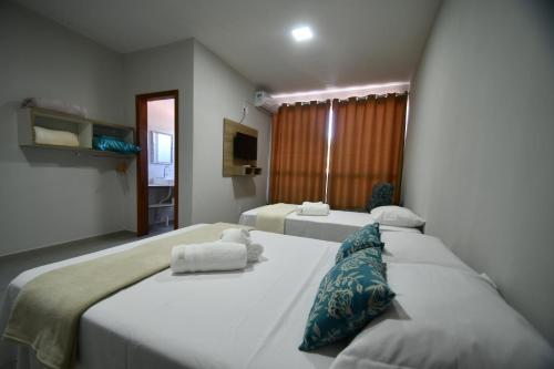拉古纳Pousada Barra Sul的两张位于酒店客房的床,配有两张sidx sidx单人床