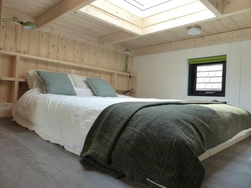雷嫩Trendy Tiny Houses Bovenweg的一间带一张大床的卧室,位于带天窗的房间