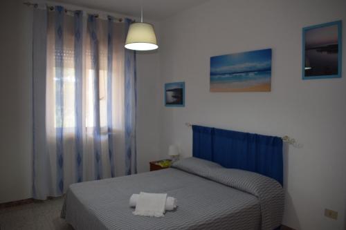 玛丽娜迪曼卡维萨Alba Chiara - Villa con Giardino的一间卧室配有蓝色的床和2条毛巾
