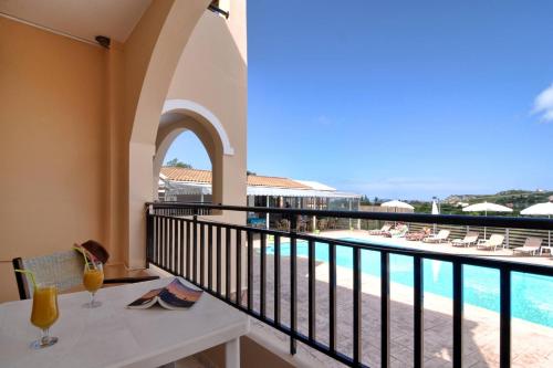 阿里拉斯Makris Apartments Arillas Corfu的阳台配有桌子,享有游泳池的景色