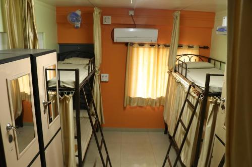 浦那Ashirwad Guest House (Male Only)的橙色墙壁的客房内设有两张双层床。