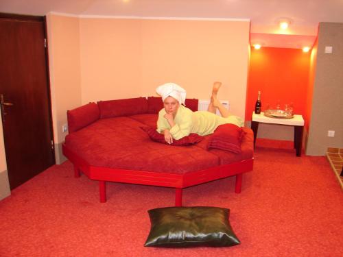 莱斯科瓦茨HOTEL VILA MITIC LUXX SPA centar的女人躺在红色的沙发上