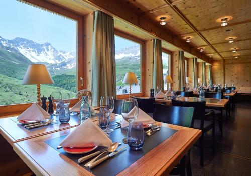 阿罗萨Hotel Stoffel - adults only的餐厅配有桌椅,位于山脉的背景中