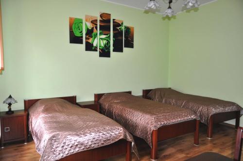 波莫瑞地区德拉夫斯科Apartament Przy Deptaku的一间设有两张床的客房,墙上挂有绘画作品