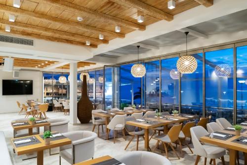 波利克罗诺Sea Level Hotel - Adults Only 16 plus的餐厅设有桌椅和大窗户。