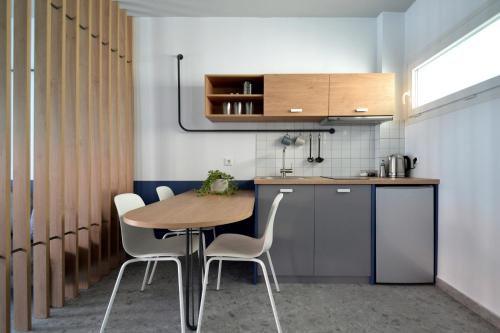 卡利塞亚-豪客迪克斯Voula Seaside Apartments的厨房配有木桌和白色椅子