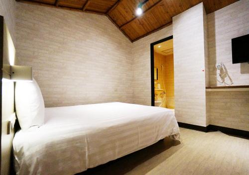 高雄远悦饭店 高雄爱河馆的卧室配有白色的床和电视。