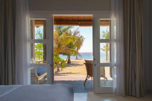 吉利美诺Meno House - Adults Only的卧室可通过门欣赏到海滩美景