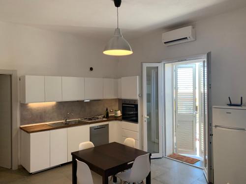 兰佩杜萨L'Argonauta的厨房配有白色橱柜和桌椅