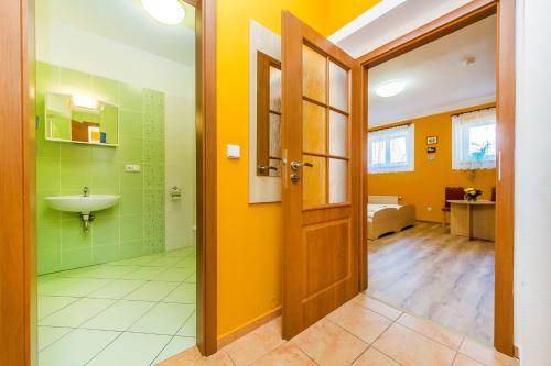 BlšanyHotel & Motorest V Údolí Zlatého potoka的浴室设有黄色的墙壁、水槽和门