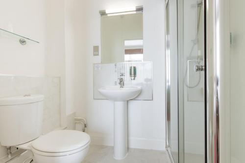 佩恩顿The Queens Hotel的白色的浴室设有卫生间和水槽。