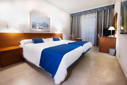 大加那利岛拉斯帕尔马斯和蔼酒店的一间卧室配有一张带蓝白色床单的大床