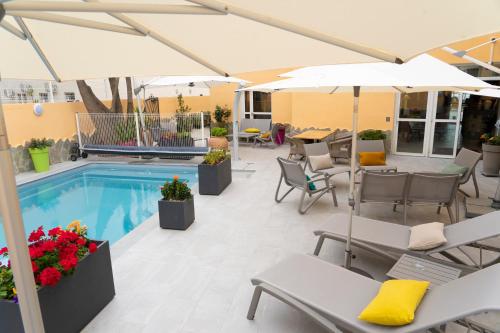 吉索纳恰Hôtel A casa di Maria Cicilia的一个带椅子和遮阳伞的庭院和一个游泳池