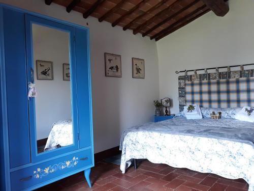 卡斯特利纳-因基安蒂Agriturismo Piemaggino的一间卧室配有蓝色的床和镜子