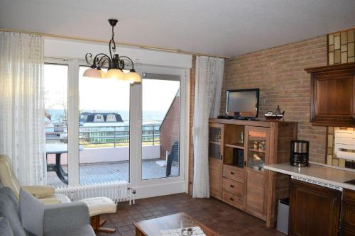 达默Haus-am-Deich-Wohnung-12的厨房以及享有阳台景致的客厅。