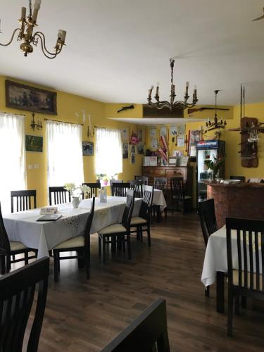 科沙林Restauracja Łania的用餐室设有白色的桌椅和黄色的墙壁
