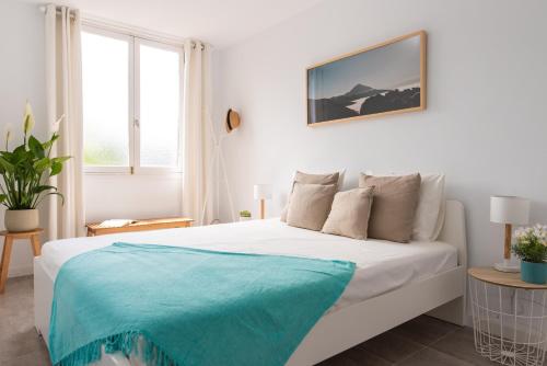 法纳贝海滩HomeForGuest BEACH APT WITH SEA VIEW & POOL, 50 STEPS TO THE SEA的白色卧室配有一张带蓝色毯子的床