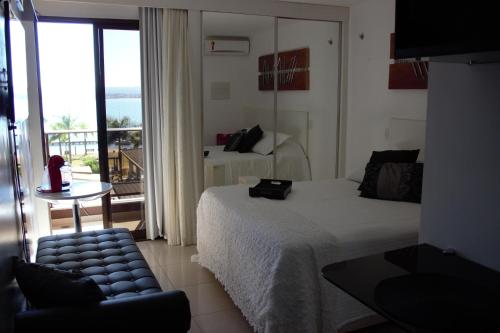 巴西利亚Life Resort的一间带一张床和一把椅子的卧室以及一个阳台