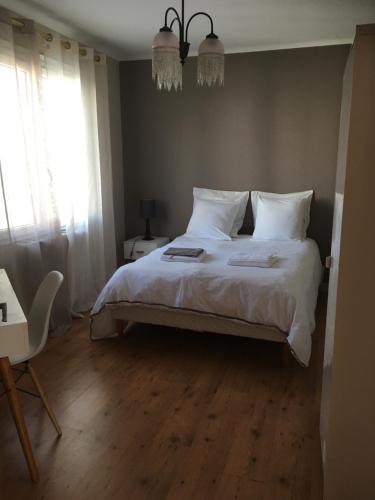 瓦讷L'Hermine的一间卧室配有一张带白色床单的床和一扇窗户。