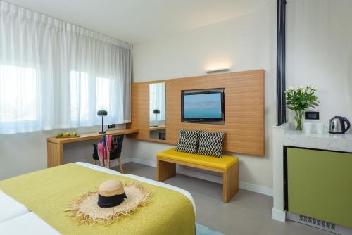 提比里亚普利马嘉里提博利亚酒店的客房设有床、电视和黄椅。