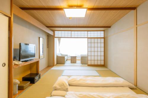 伊东Kameya Rakan的日式客房配有一张床和电视。